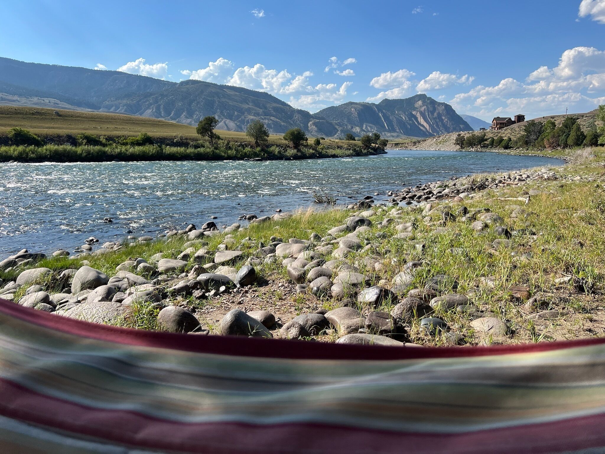 A river with a rocky shore and mountains in the background.