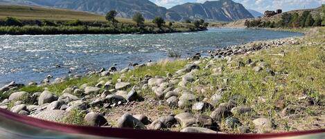A river with a rocky shore and mountains in the background.