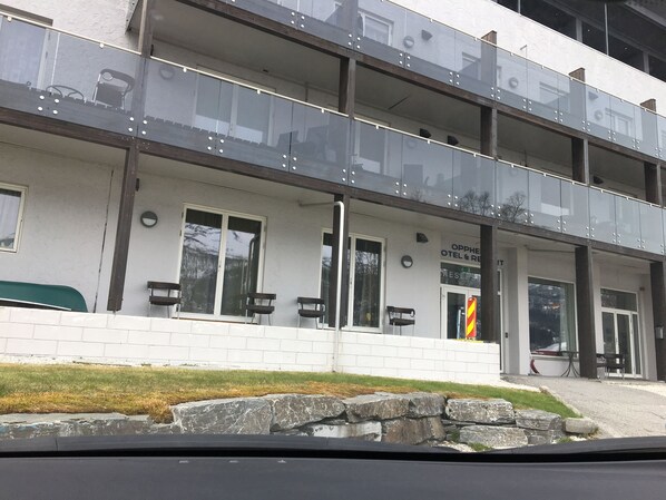 A modern hotel with a glass balcony, white exterior walls, and a sign indicating it is an Oppi Hotel & Restaurant. - Oppheim Apartments (Voss)