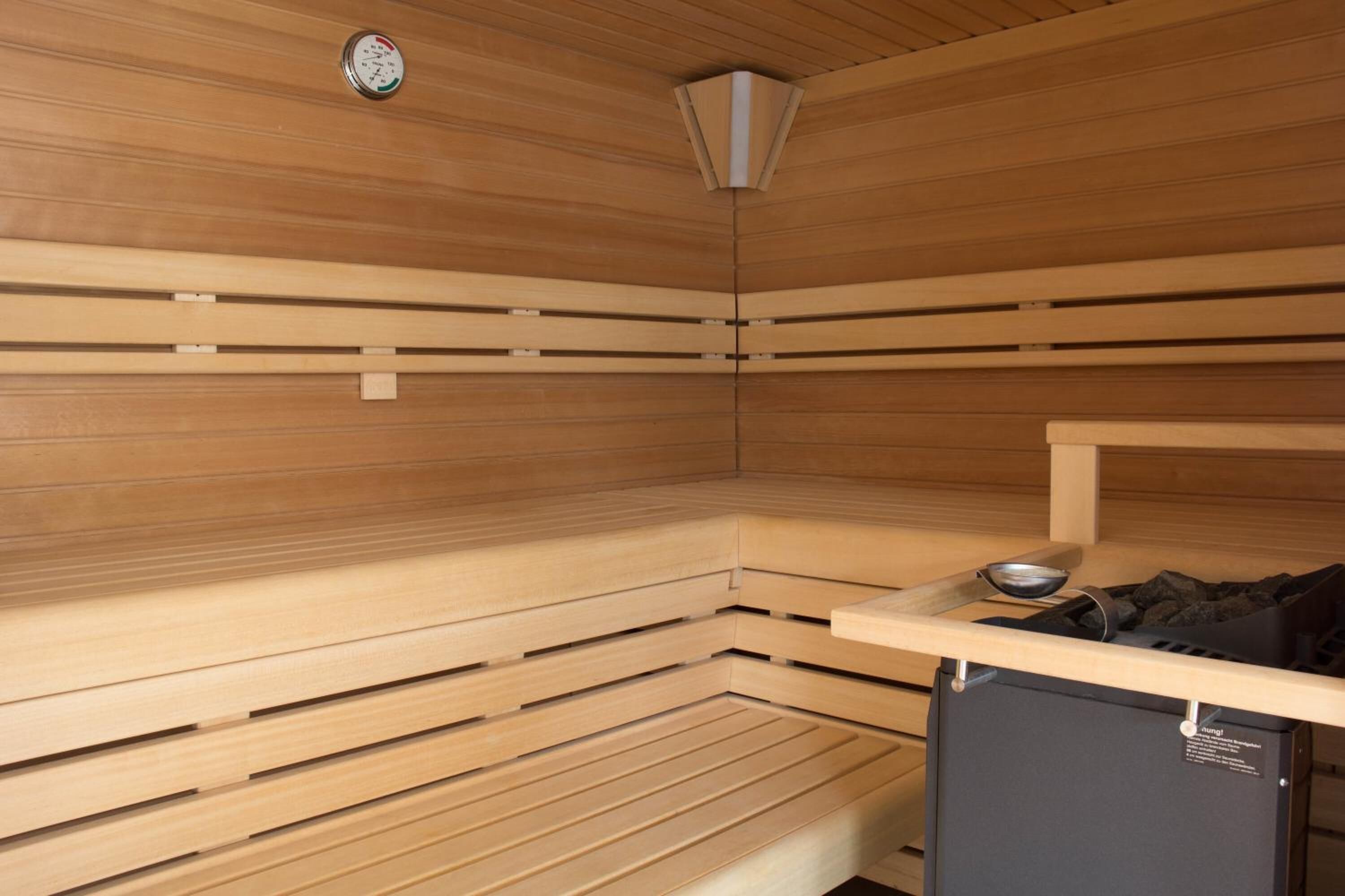 A sauna room with wooden benches and a small black heater.