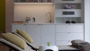 Casa de banho moderna com lavatório embutido, espaço para toalhas e uma pequena mesa de cabeceira.