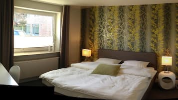 Ein Hotelzimmer mit Bett, zwei Nachttischlampen, einem Fenster und Blick nach draußen.