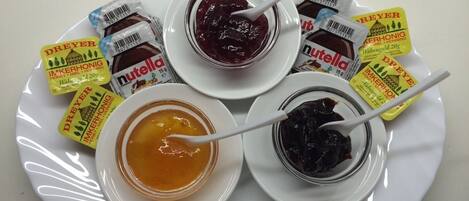 A plate with three jars of honey and two jars of Nutella.