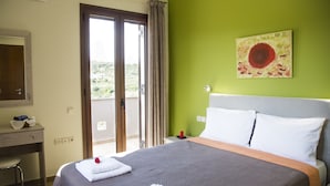A hotel room with a bed, a desk, and a view of the outdoors. - Villa Saint George (Rethymno)