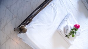 A bed with white linens, a metal bed frame, and a pink flower on the pillow. - Harma Rooms & Apartments (Apokoronas)