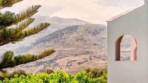 A white building with an arched window, surrounded by greenery and a mountainous landscape in the background. - Harma Rooms & Apartments (Apokoronas)