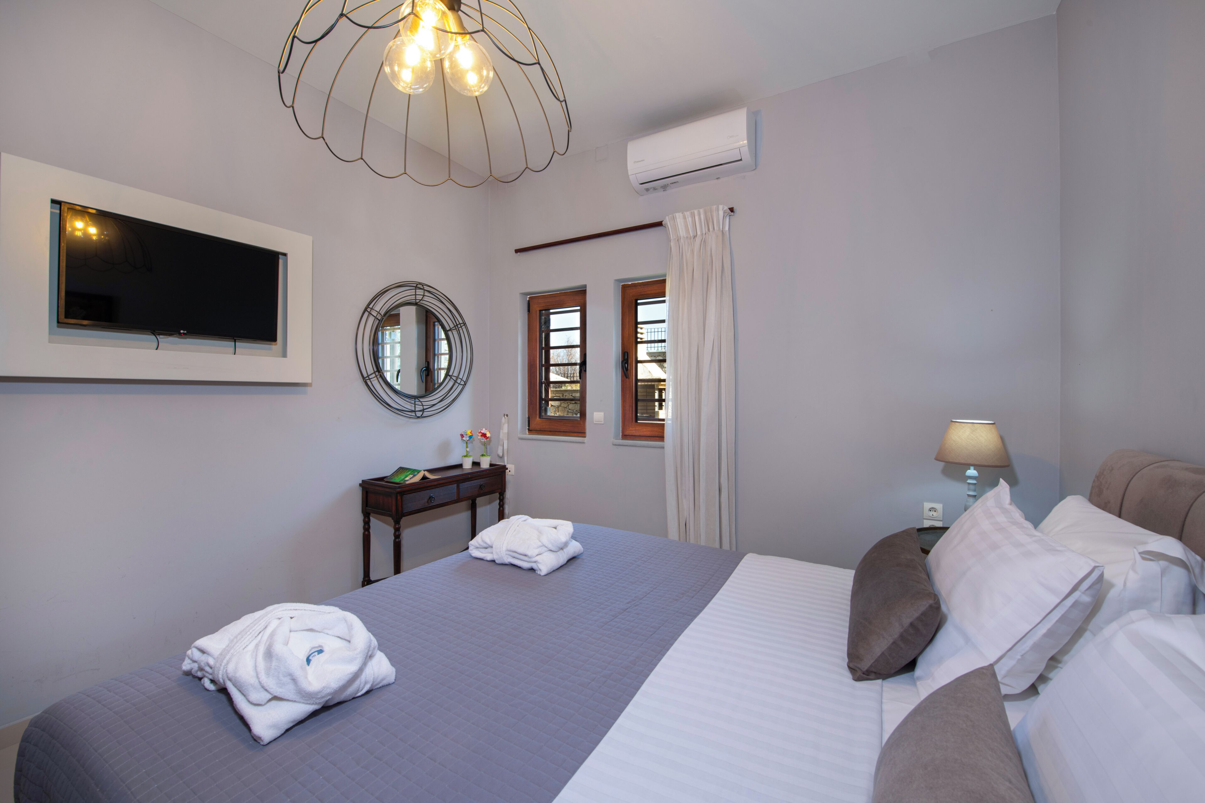 Habitación de hotel con cama, televisión, escritorio y lámpara.