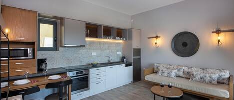 A modern kitchen with a dining area, a sofa, and a round table with wine glasses.