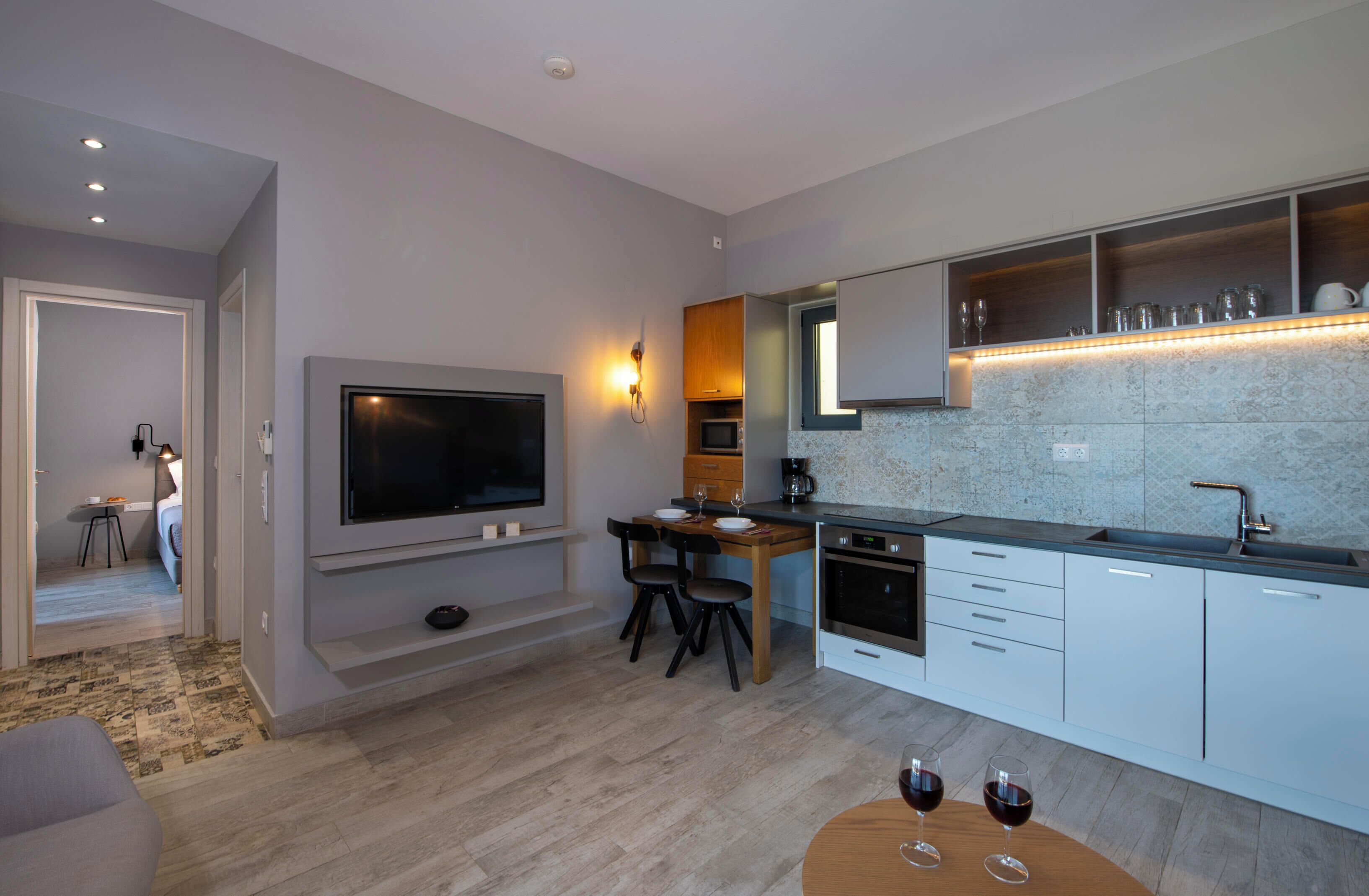 A modern kitchen with a flat-screen TV, wooden dining table, and built-in appliances.