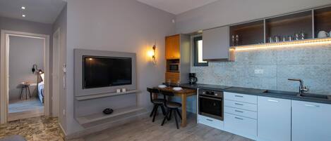 A modern kitchen with a flat-screen TV, wooden dining table, and built-in appliances.
