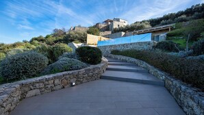A stone pathway leading to a building with a stone facade and a blue roof. - Thea Villas Complex (Apokoronas)