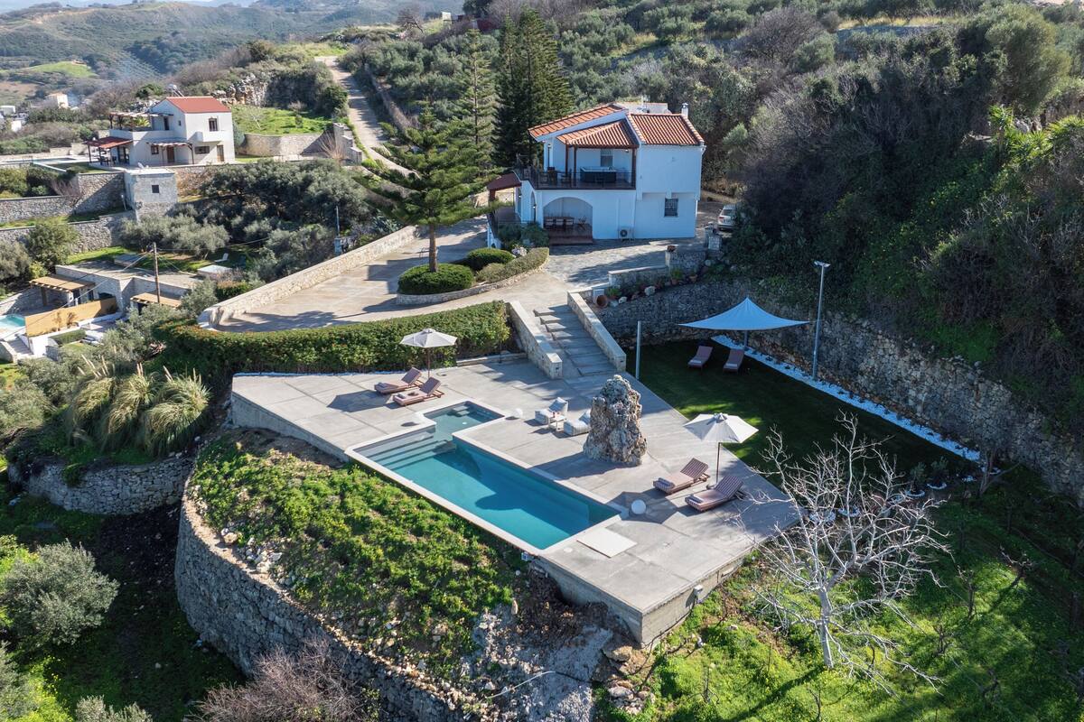 Una villa con piscina, mobiliario exterior y un muro de contención de piedra.