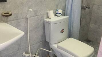 Une salle de bain avec des toilettes, un lavabo et une douche.