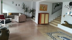 Un vaste espace de vie comprenant un canapé, des fauteuils, une table basse et un escalier menant à l’étage supérieur.