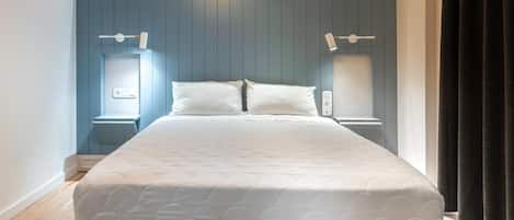 A modern bedroom with a large bed, built-in shelving, and bedside lamps.
