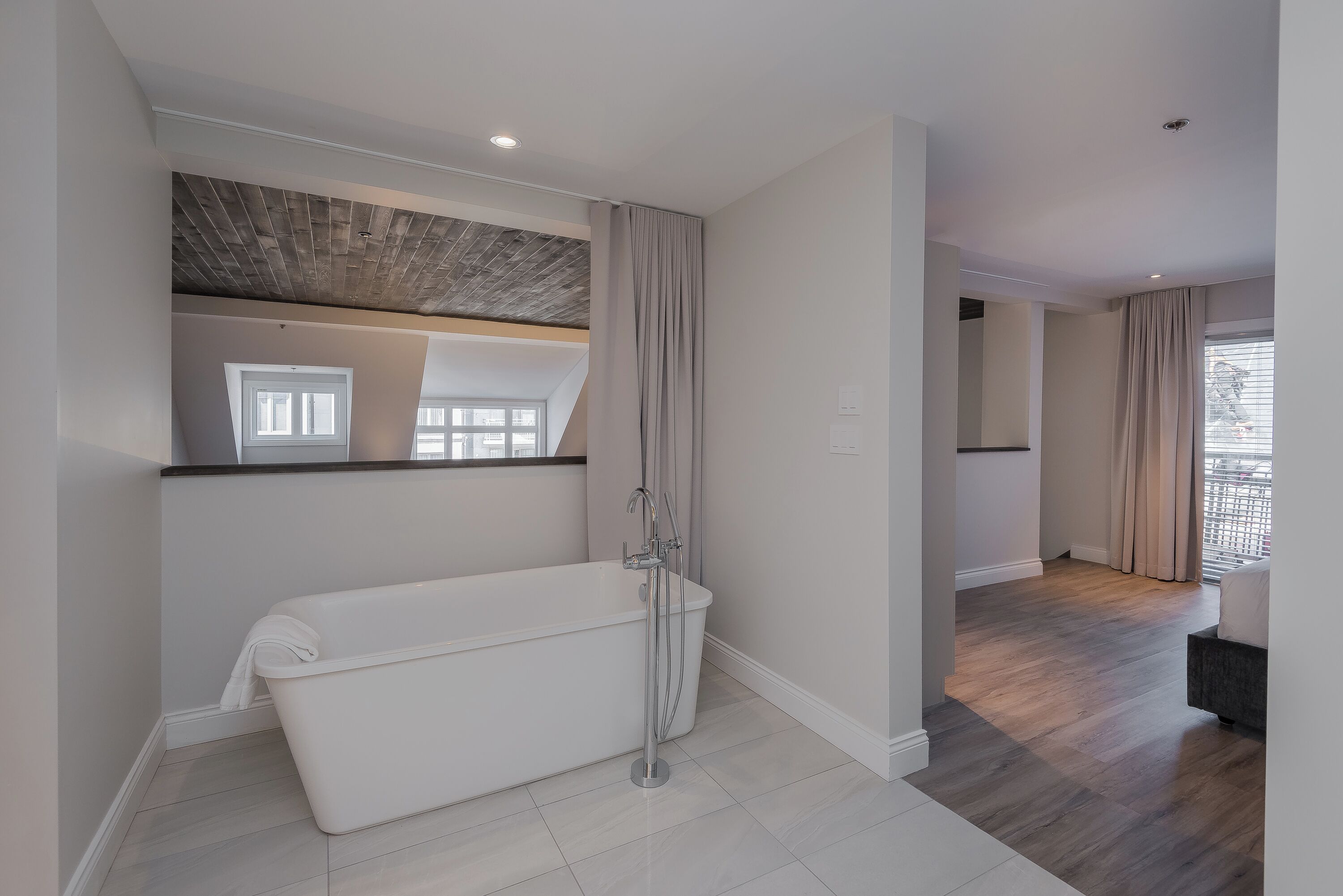 A modern bathroom with a freestanding bathtub, a shower, and a large mirror.
