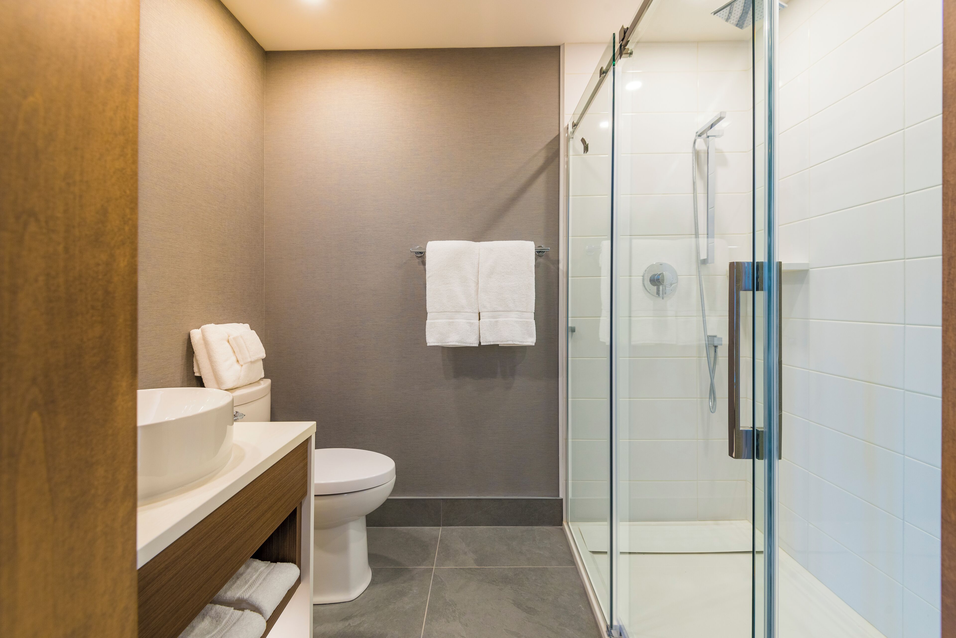 Une salle de bain moderne avec une douche à parois de verre, un lavabo blanc et des toilettes.