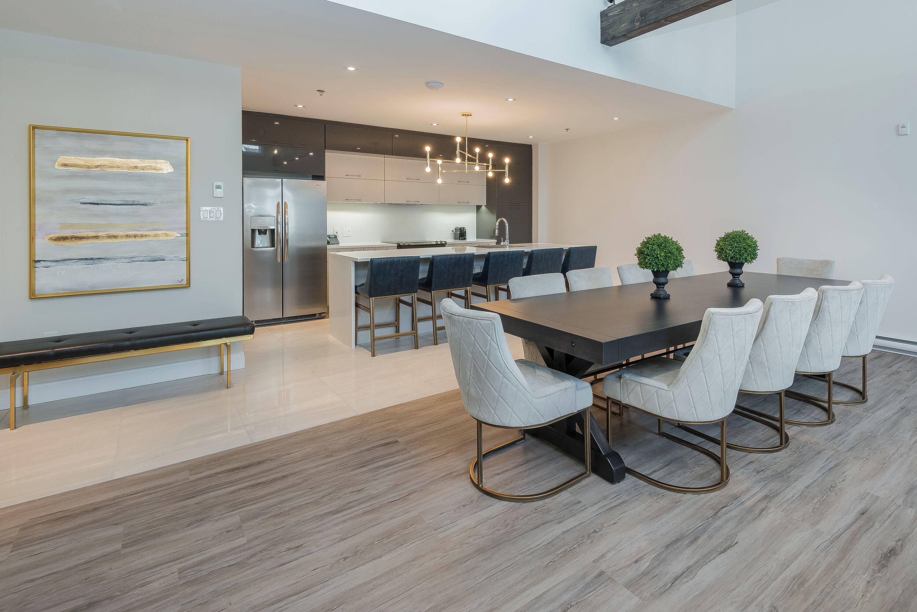 Una cocina moderna con una isla central, electrodomésticos de acero inoxidable y un comedor con una mesa grande y sillas.