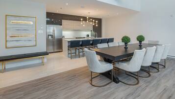 A modern kitchen with a central island, stainless steel appliances, and a dining area with a long table and chairs.