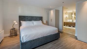 Un dormitorio moderno con una cama grande, lámparas de noche y suelo de madera.