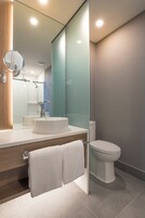 Un baño moderno con cabina de ducha de vidrio, un lavabo blanco y un inodoro.