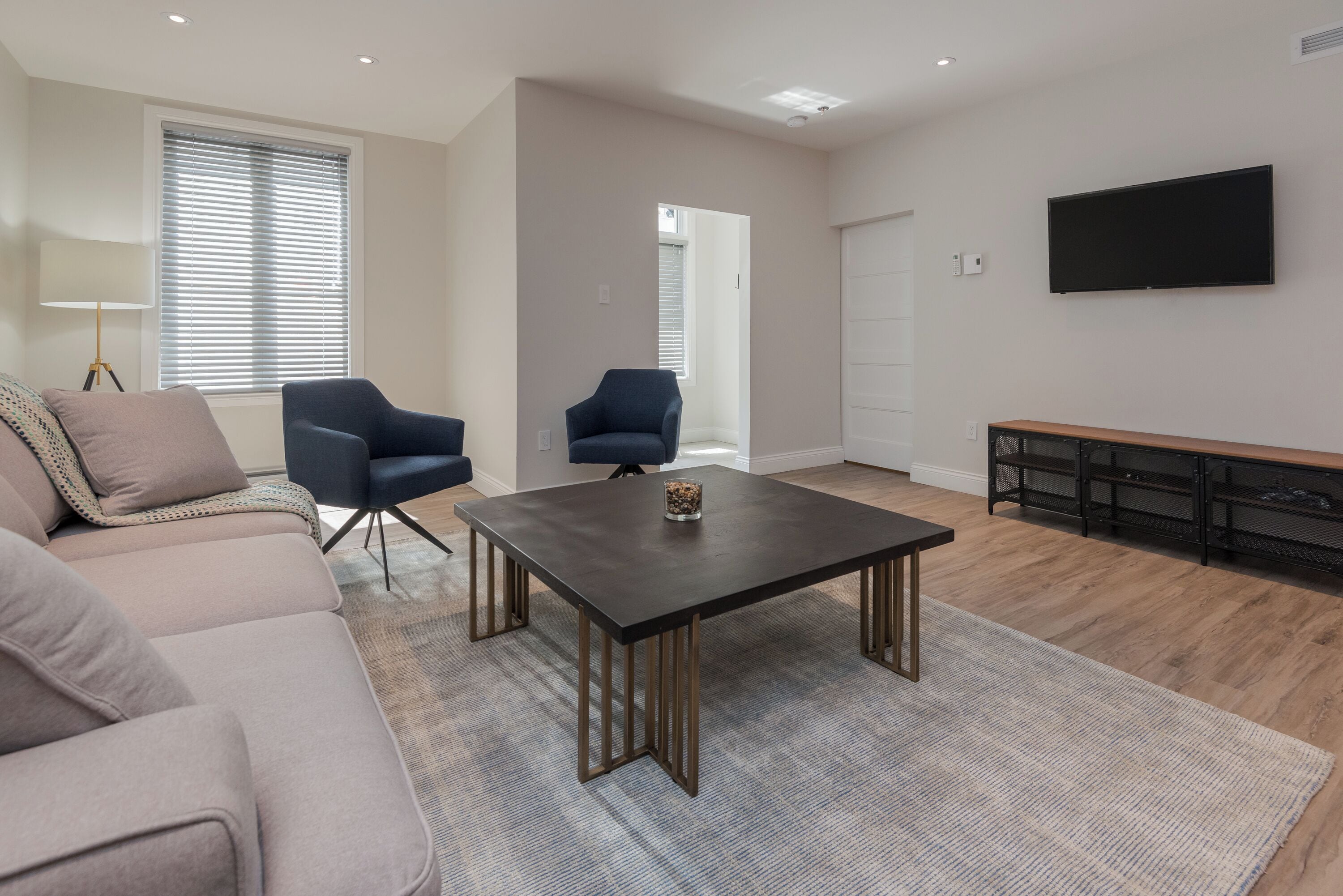 A modern living room with a sofa, two armchairs, a coffee table, a TV, and a fireplace.