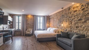 A modern bedroom with a stone wall, a bed, a desk, and a sofa. - La Maison Kent - Par Aneyro (Québec City)
