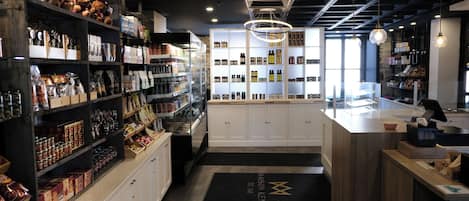A modern retail space with shelves stocked with various products, a central counter, and a decorative hanging light fixture.