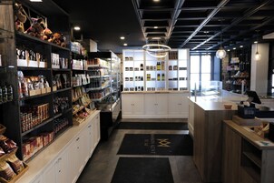 Un espacio comercial moderno con estanterías llenas de diversos productos, un mostrador central y una lámpara colgante decorativa.