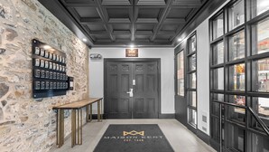 A hotel entrance with a stone wall, a display of phone cards, and a black doormat with the hotel name. - La Maison Kent - Par Aneyro (Québec City)