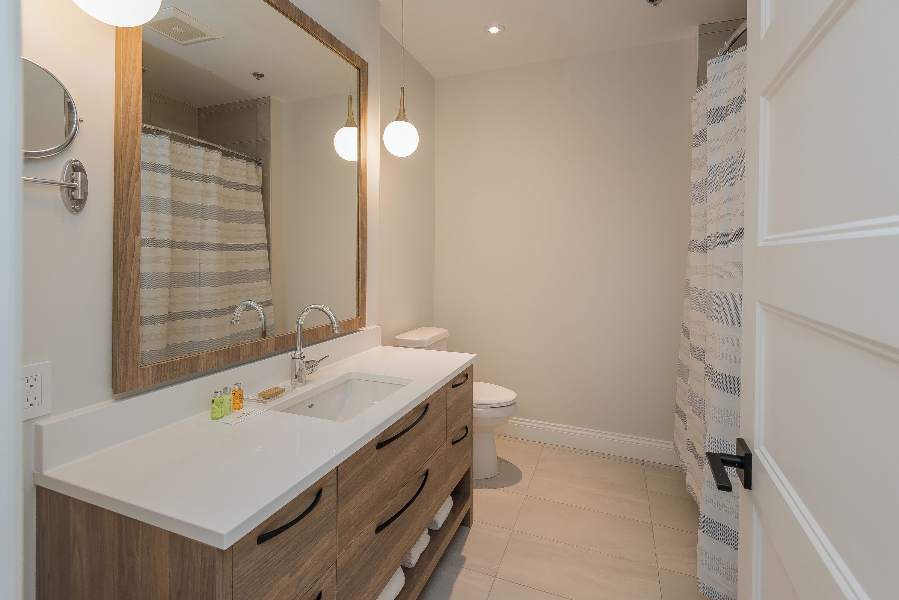 Une salle de bain moderne avec un lavabo blanc, un meuble-lavabo en bois et un grand miroir.