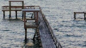 Een houten steiger die zich uitstrekt in kalm water, met een zonsondergang op de achtergrond.