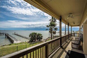 Una terraza de madera con vistas al océano y un muelle.