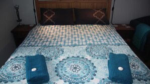 A bed with a patterned bedspread, two pillows, and two folded towels.