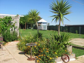 A garden with a birdbath, a gazebo, and a wheelbarrow.