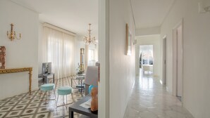 Un'ampia zona giorno con pavimento decorato, un lampadario e vista su un'altra stanza.