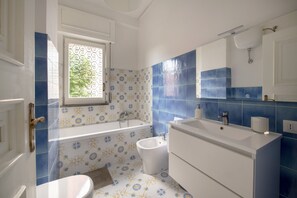Un baño con bañera, bidé y un espejo grande.