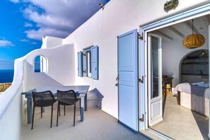 Relax in a serene outdoor space with a panoramic sea view, featuring a curved wall design and comfortable seating for two.