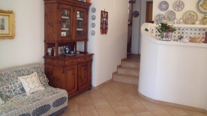 Un salón con un aparador de madera, un sofá estampado y una escalera que lleva a otra habitación.
