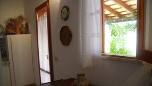 Una cocina con una mesa de madera, un cuenco decorativo y una ventana que da a zonas verdes.