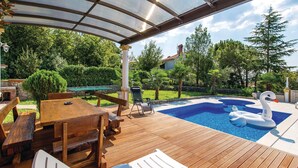A wooden deck with a pool, lounge chairs, and a swan float. - Cozy apartment in Matulji with WiFi (Matulji)