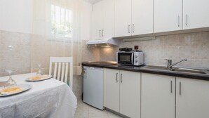 A compact kitchen with white cabinets, a microwave, a toaster, and a small refrigerator. - Cozy apartment in Matulji with WiFi (Matulji)