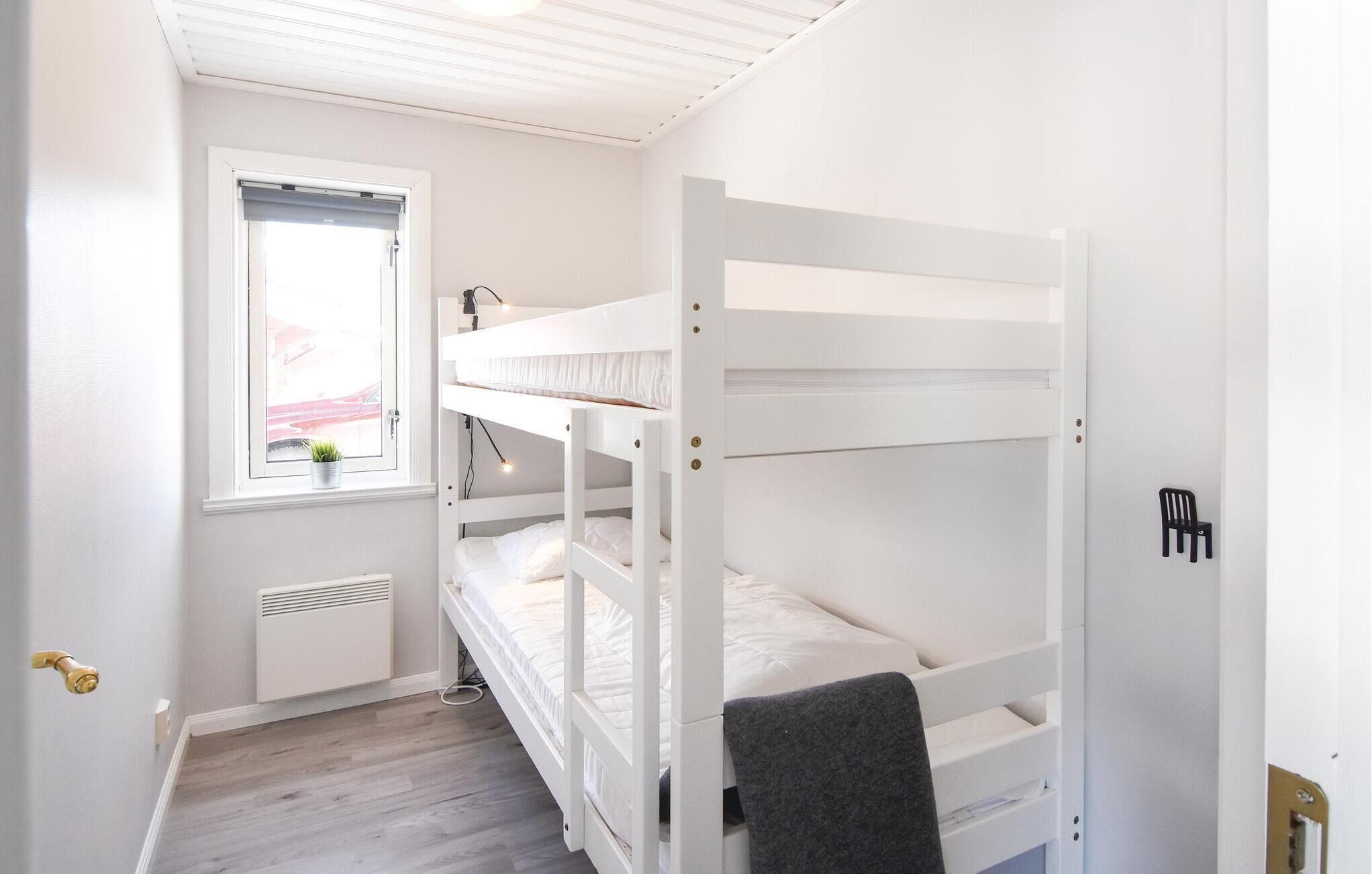 Dormitorio con literas, ventana, radiador y puerta.