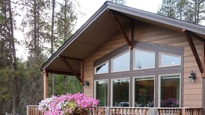 Une cabane en bois à deux étages, dotée d’un balcon, de grandes fenêtres et de jardinières suspendues.