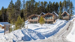 Une station de ski dotée de plusieurs chalets en bois, d’une piste enneigée et d’un ciel dégagé.