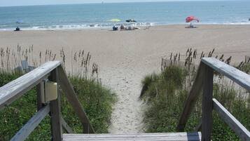 Une promenade en bois mène à une plage de sable, d’où l’on a une vue dégagée sur l’océan.
