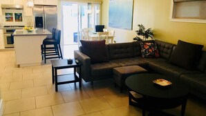 Un salon moderne comprenant un canapé d’angle, une table basse et un coin repas avec une table et des chaises.