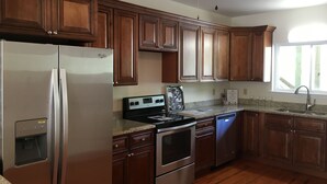 A kitchen with wooden cabinets, stainless steel appliances, granite countertops, and a window with natural light.