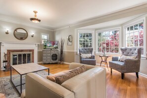 A living room with a fireplace, two armchairs, a sofa, a coffee table, and a television.