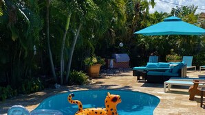 A swimming pool with inflatable toys, a lounge area with a blue umbrella, and a brick building in the background. - Deerfield Beach House and Pool
https://my.matterport.com/show/?m=6txjncxb5Lo (Deerfield Beach)